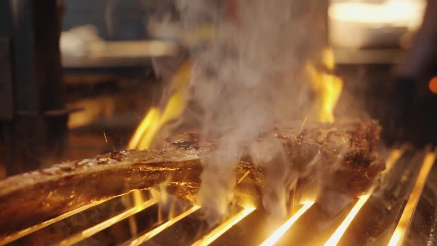 A chef is cooking a steak on the hot flame