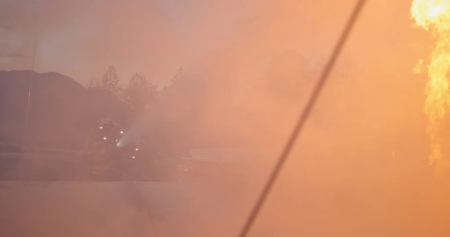 A firefighter sprays water on a home as flames grow taller
