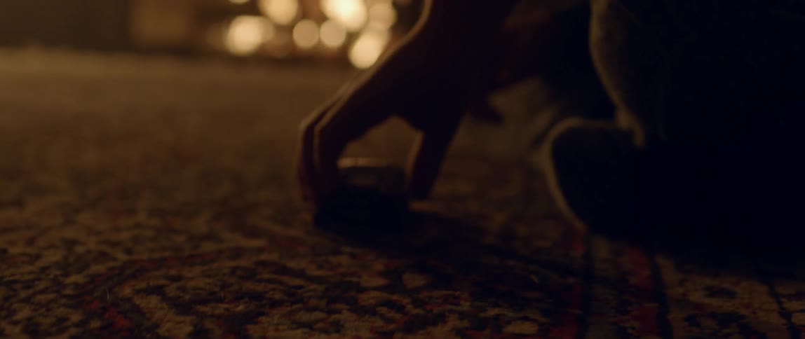 A child rolls a toy car on the rug in front of the fireplace