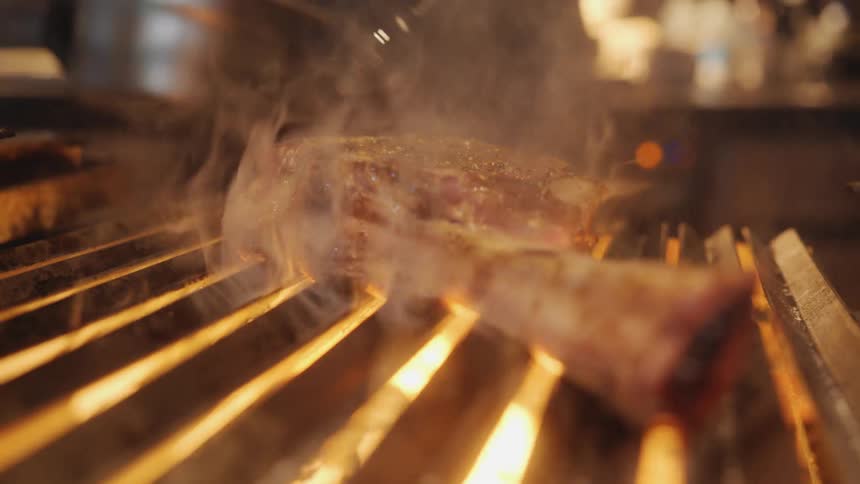A chef bastes a steak on the grill
