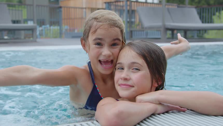 Two girls swimming in a pool together