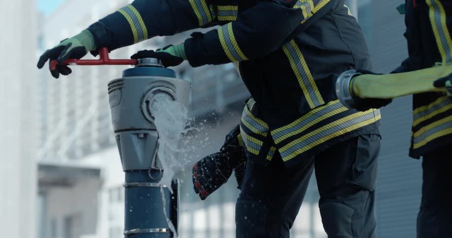 Two firemen opening a fire hydrant on the street to connect a hose