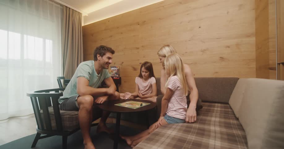 Family of four playing tabletop game on the living room at home