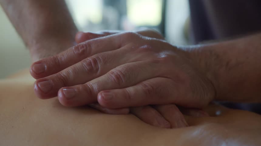 Overlapping hands slowly move across somebodys back
