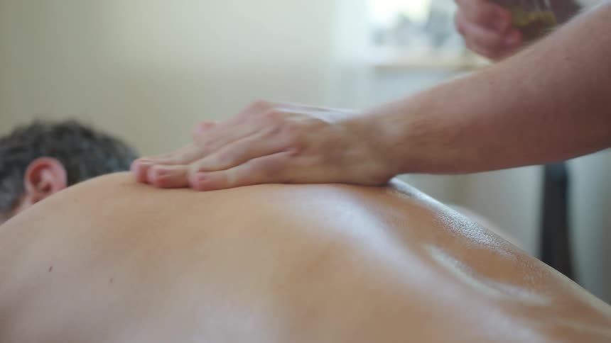 Man gives man massage in massage parlor