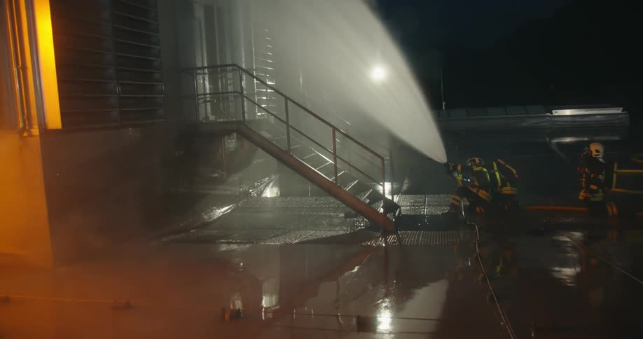 A firefighter uses a hose to put on flames engulfing a trailer