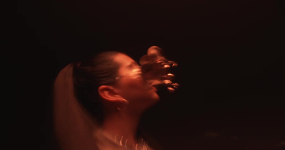 A woman with a necklace in a room with lights flashing above