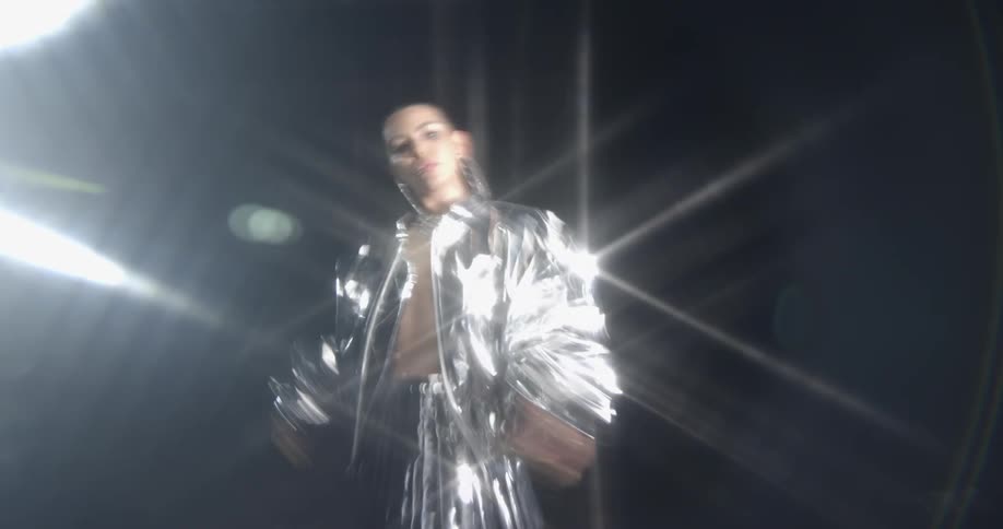 A woman dancing outdoors at night with a large light
