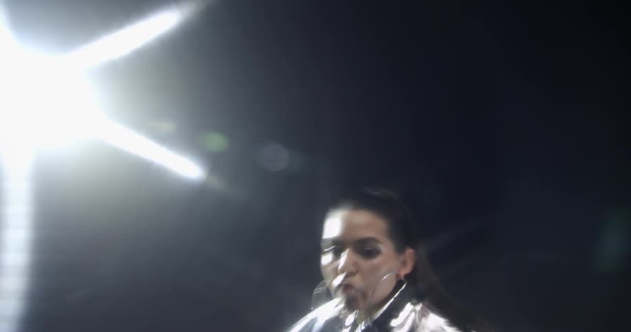 Bright lights shine and reflect off the silver clothing worn by a model