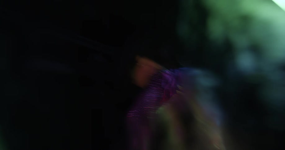 Woman wearing crystal studded outfit dance and moves under colored lights
