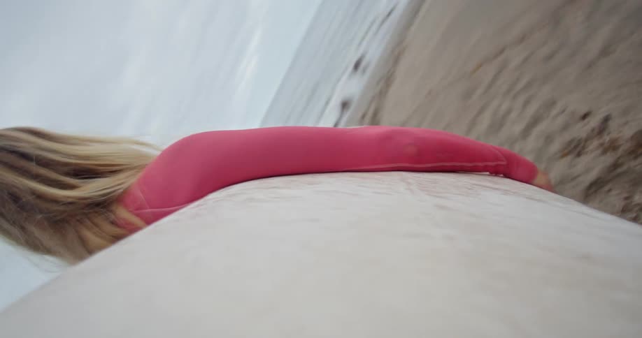 A woman sets her surfboard down on the beach