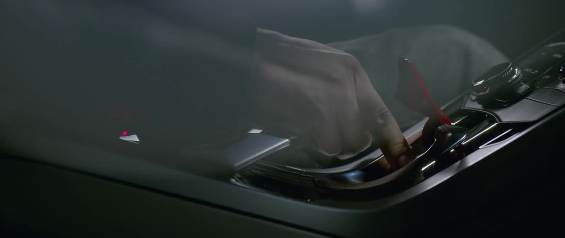 A driver presses the engine start button on a sports car
