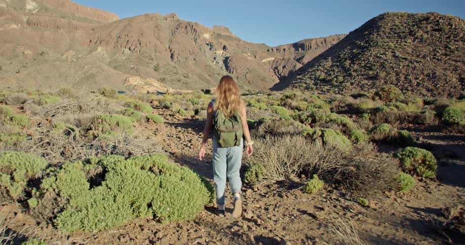 A woman hikes in the mountains while carrying a backpack