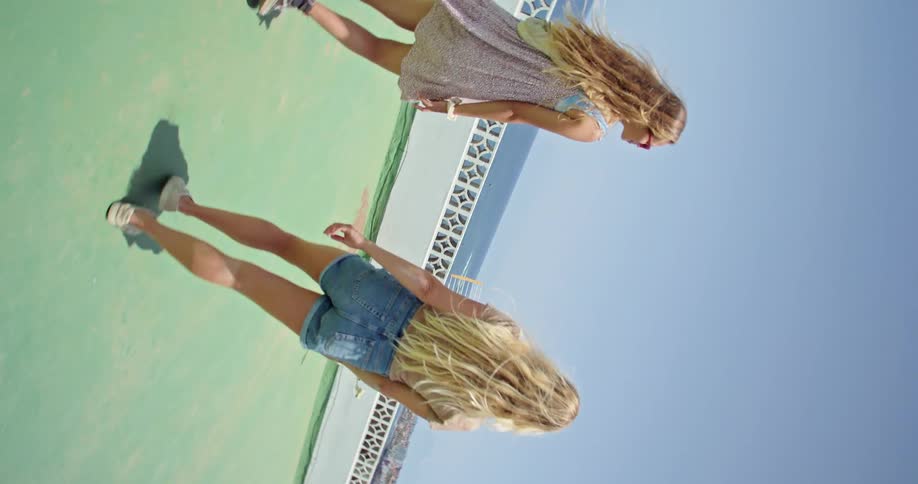 Two women walk on the rooftop of a building to take in views of the ocean below