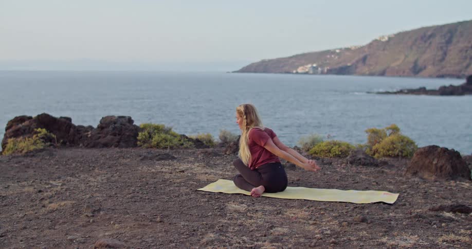 A woman doing yoga on a cliff