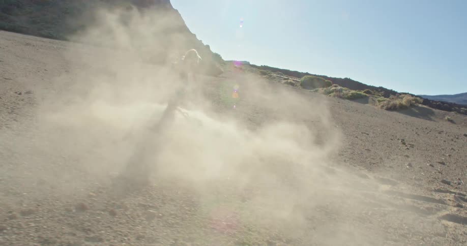 A young woman is scraping a stick in the dirt making dust in desert wilderness