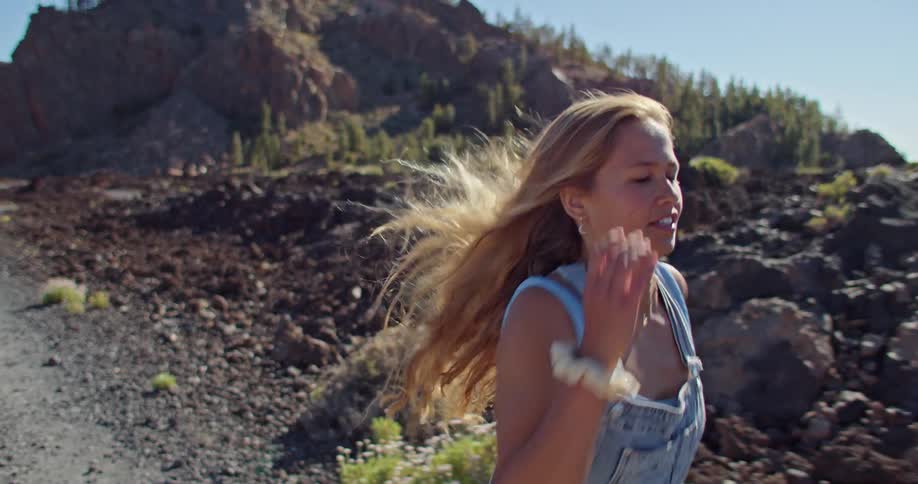 A woman in denim overalls sprints through a canyon