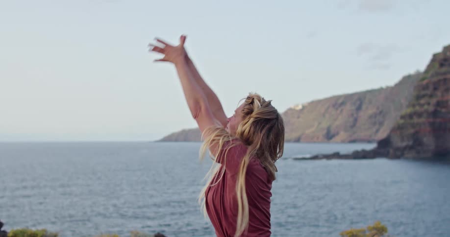 A woman with long blond hair is doing yoga exercise on a mat next to lake