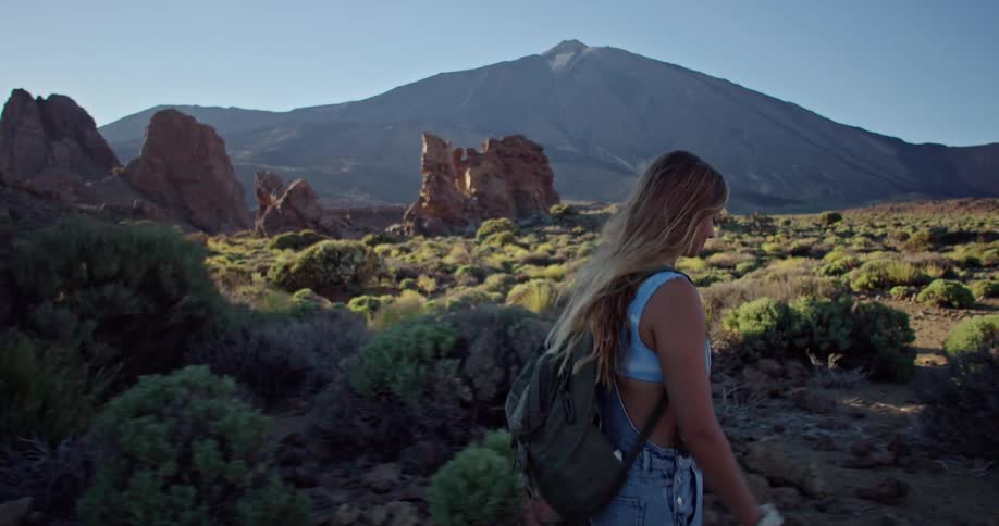 A woman is hiking a trail in the mountains