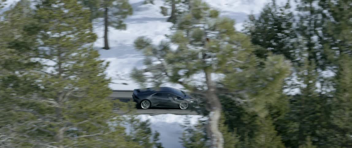 A black car speeds down a wet road in the winter