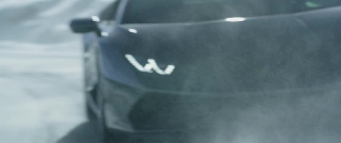A black car speeds down a mountain road in the winter
