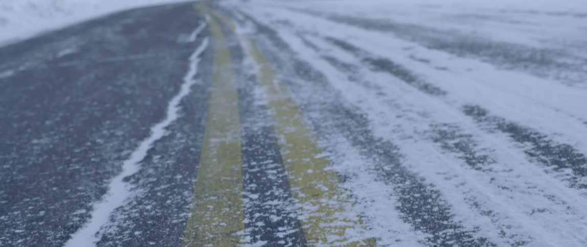 Snow is scattered along a winding mountain road
