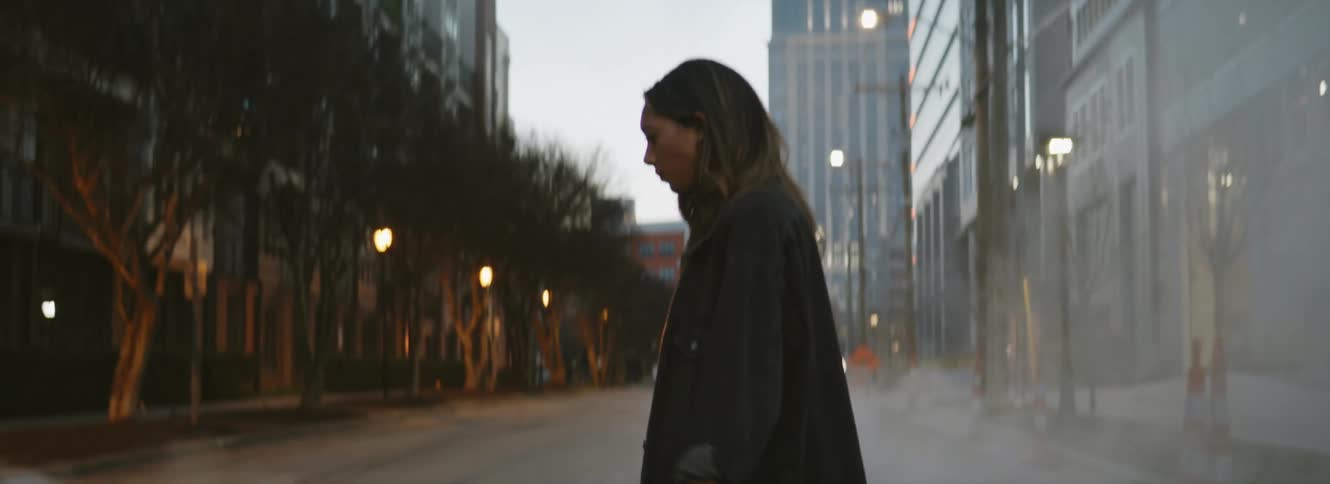 A woman looks up as she crosses a city street with steam billowing up
