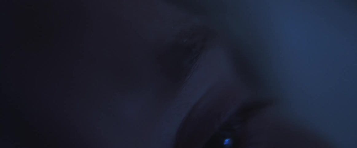 A person under blue light with an up close look at their eye and head