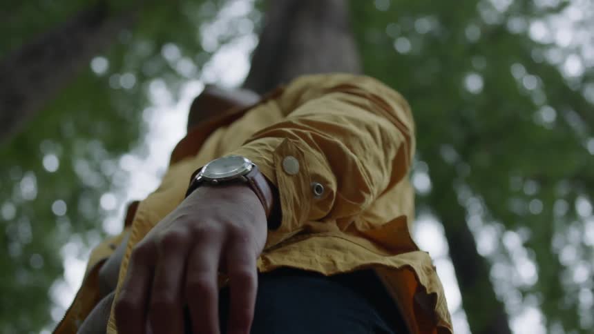 Man stands outdoors under tall trees looking around
