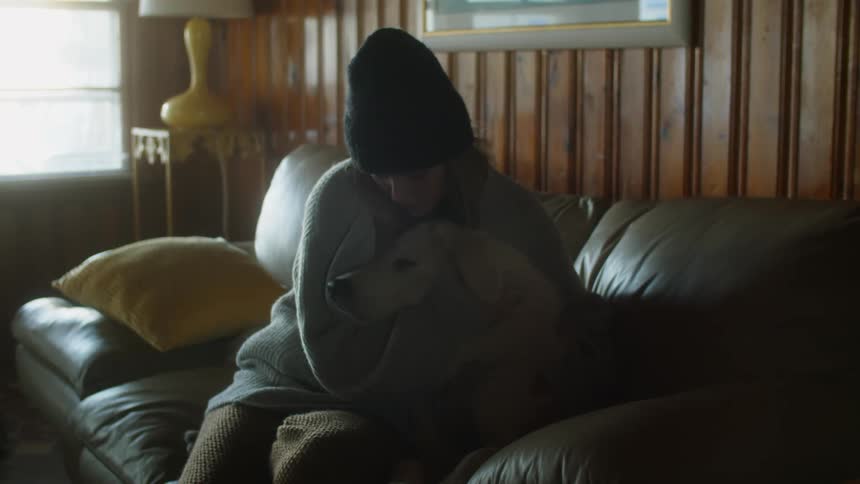 Young woman hugs a dog sitting on a couch at home