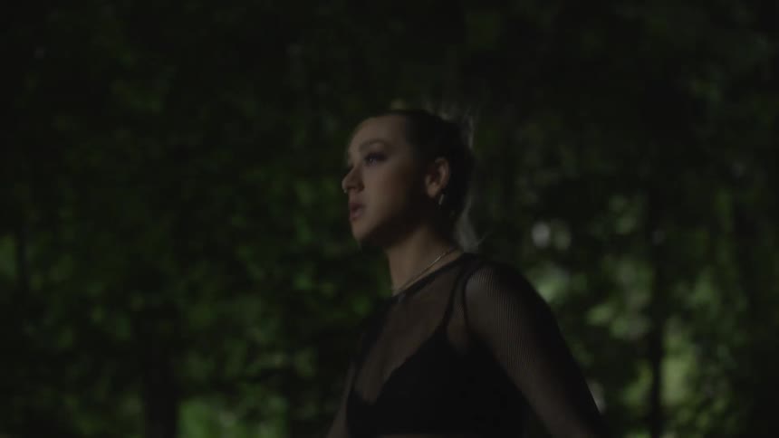 A woman is walking with woods behind her