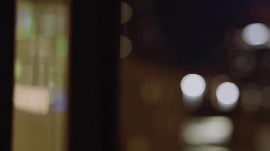 A city street is a blur of lights from buildings and shops