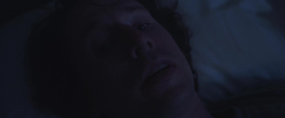 A man laying in a bed looking frightened