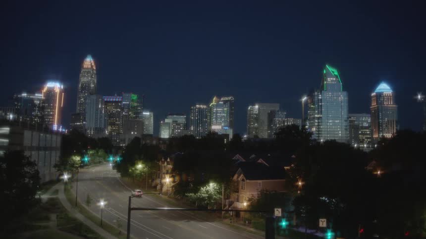 A car moves down an empty road at night in a large city