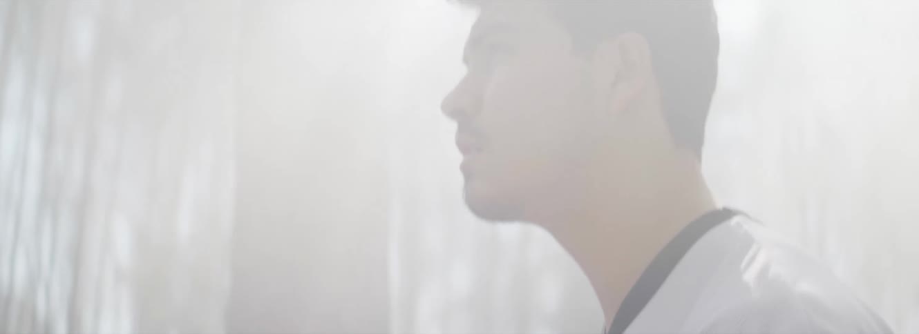 Man with goatee beard and white shirt walks in the fog in the forest looking at the sun