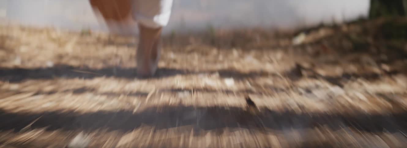 Man wearing white pants running through the smoke on the forest trail