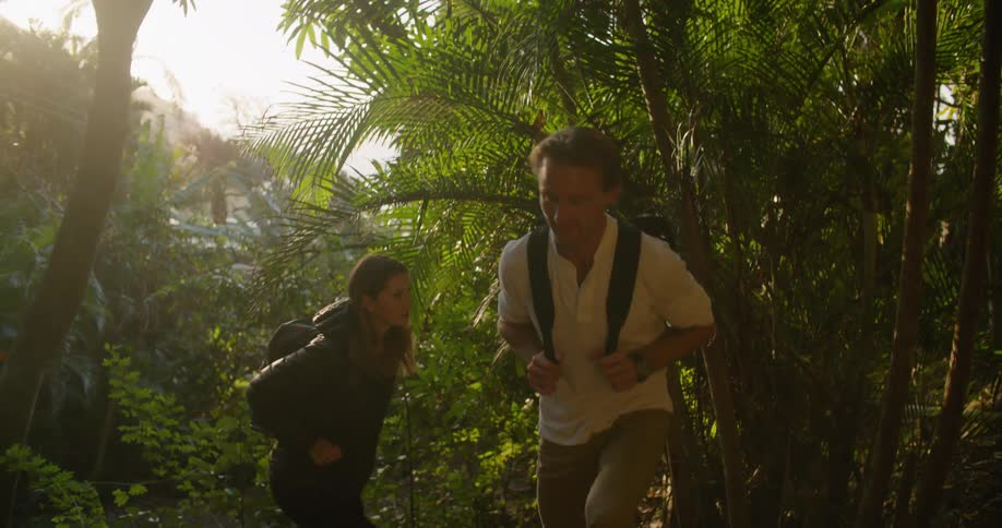 Young couple hiking through a tropical forest at sunset