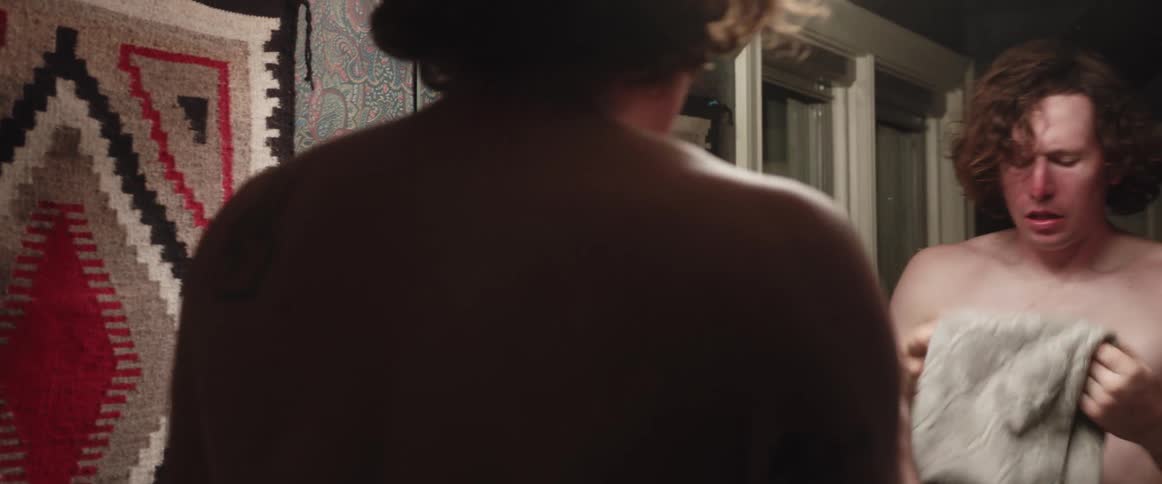 A man is in the bathroom and washing his face with a towel