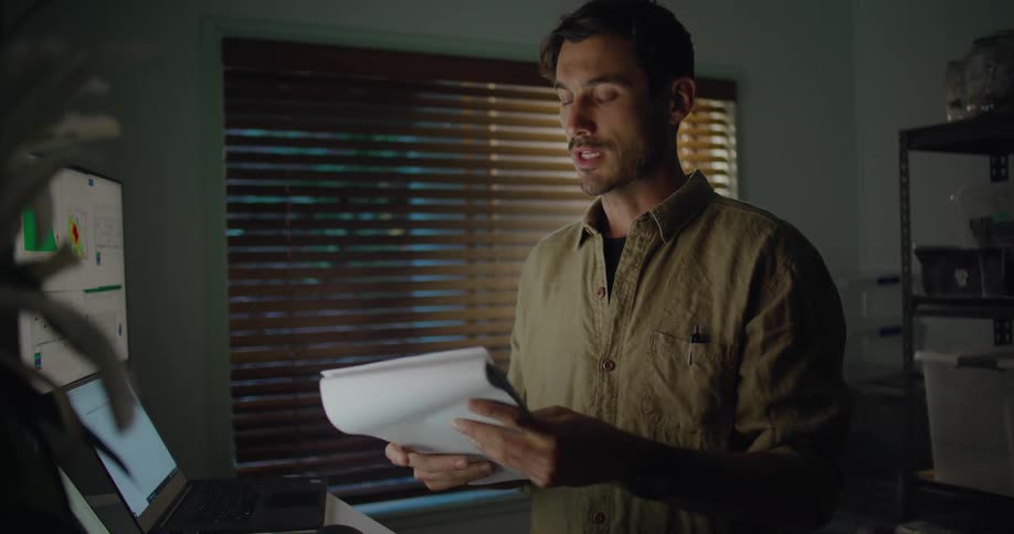 Man working at the office talks on a video call while reading a notebook