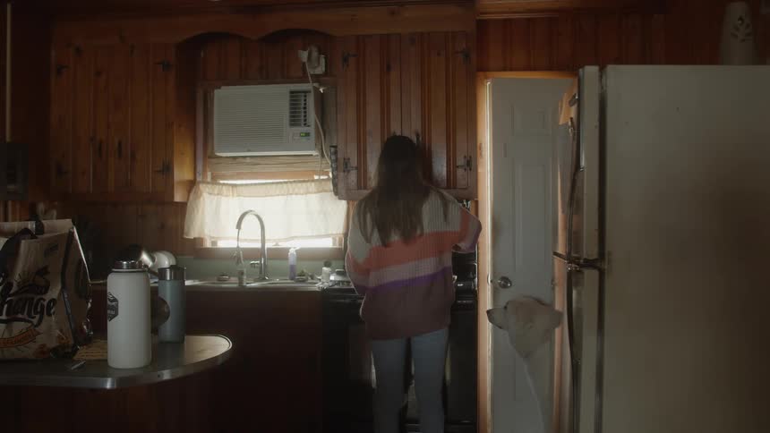 A woman in a kitchen with a dog next to her