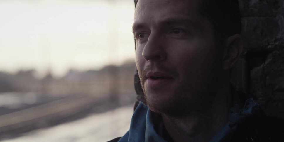 A man is sitting and talking next to a window