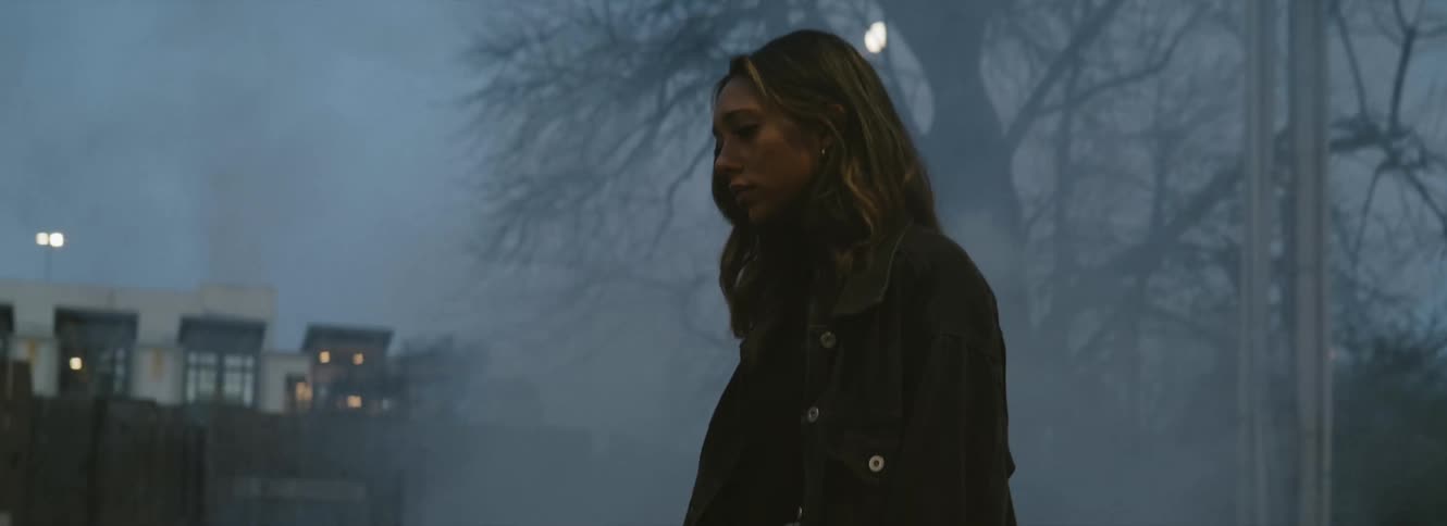 Young long haired woman standing on the smoky city street at evening
