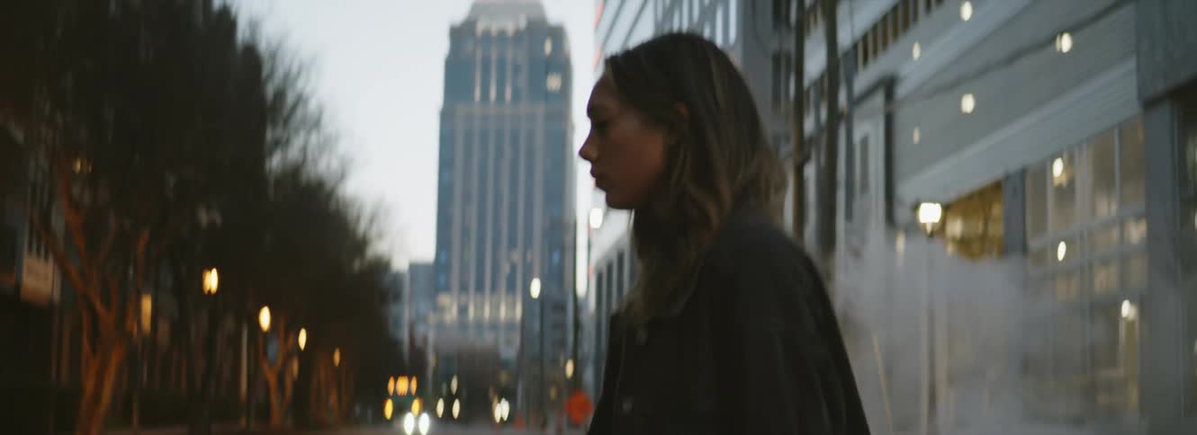 A woman is walking through a downtown city at dusk