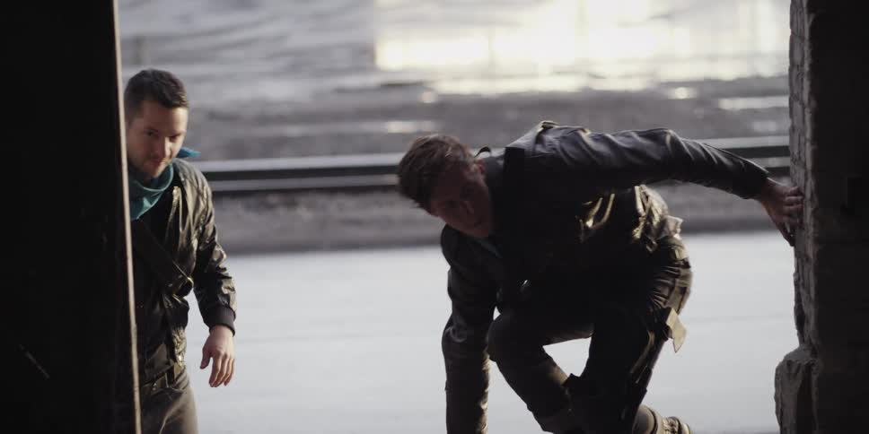 Two young men open the door of a warehouse and walk inside