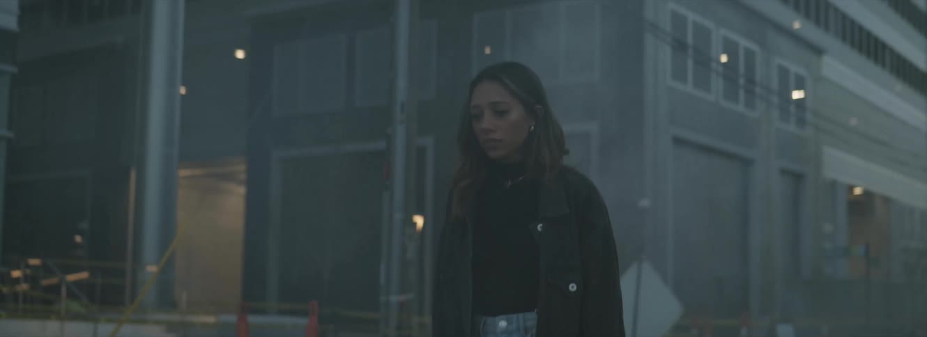 Young woman walking through the smoke on the city street at evening