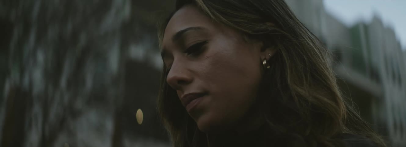 Woman with brown hair and earrings looks down in a bad mood in the city street
