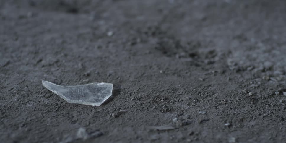 A shard of glass sliding on dirt ground