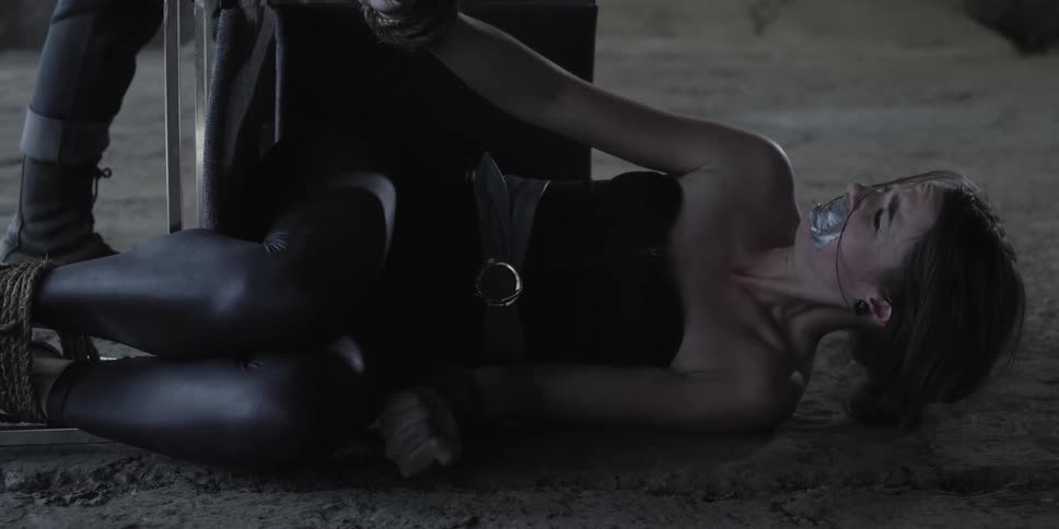 A woman gagged and tied to a chair is yanked up off the ground by a man