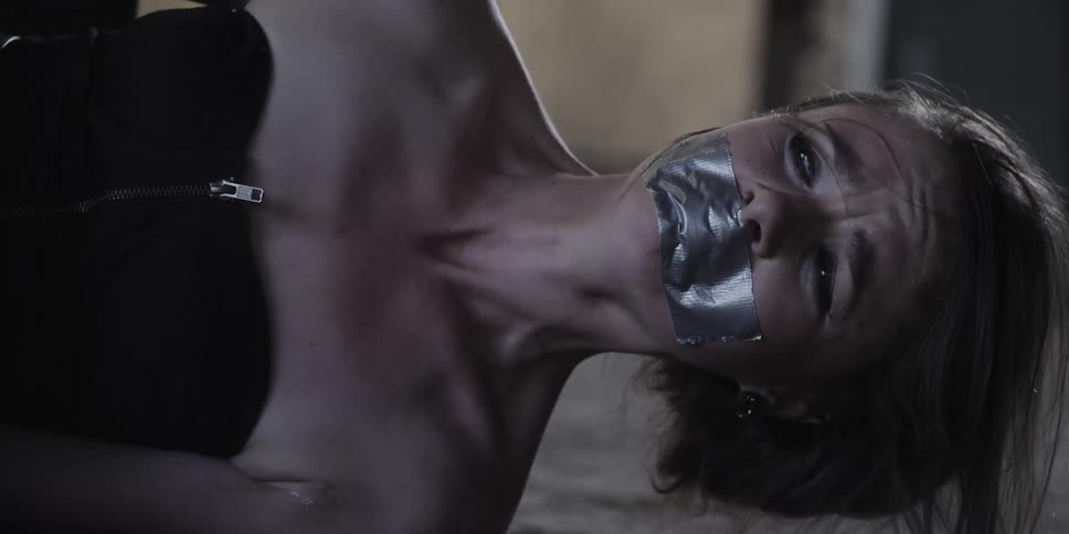 A young woman with her mouth taped shut lies on the floor and cries in fear