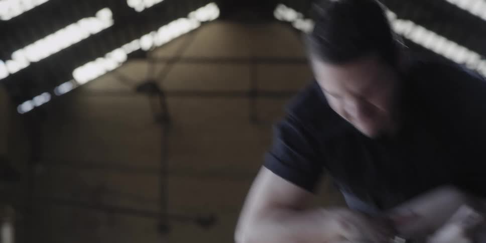 Man violently moves a gagged woman tied to a chair inside a warehouse